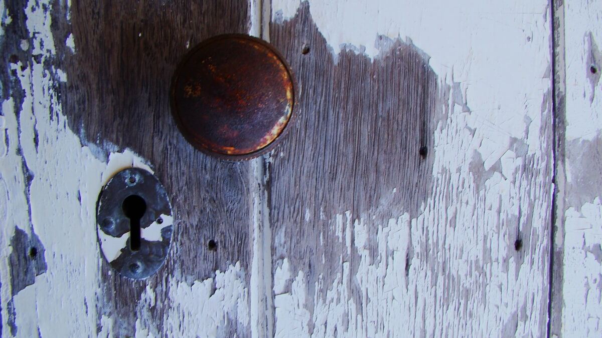 Old door with layers of worn, peeling paint around the handle