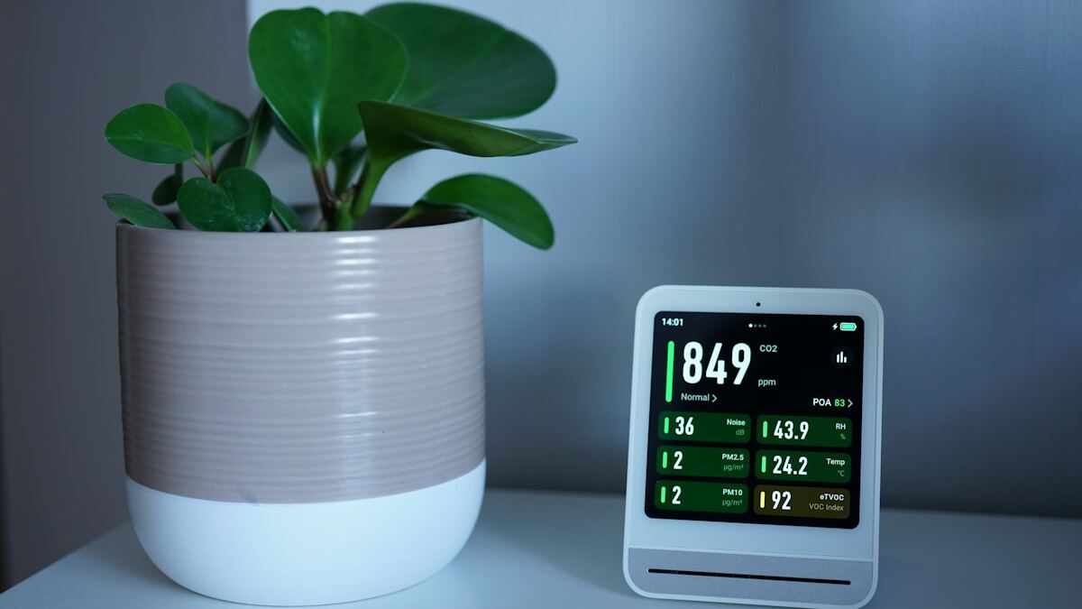 Indoor air quality monitor showing VOC and particulate readings on a shelf